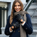 Stijlvolle zwarte leren auto handschoenen voor dames, gedragen in een elegante look met blauwe jas en sjaal.