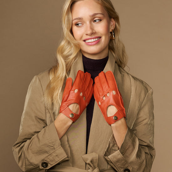 Women's orange lambskin driving gloves with perforated finger panels and snap wrist