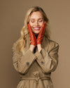 Women's orange lambskin driving gloves on hands, perforated touchscreen fingertips