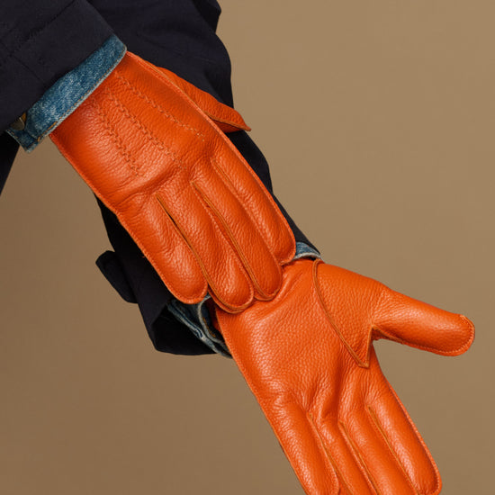 Orange leather gloves with stitched fingers and blue cuff lining detail