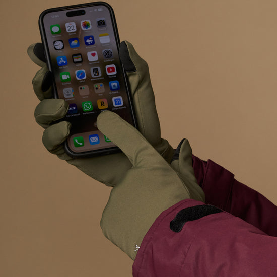 Olive green activity gloves operate a smartphone with touchscreen fingertips
