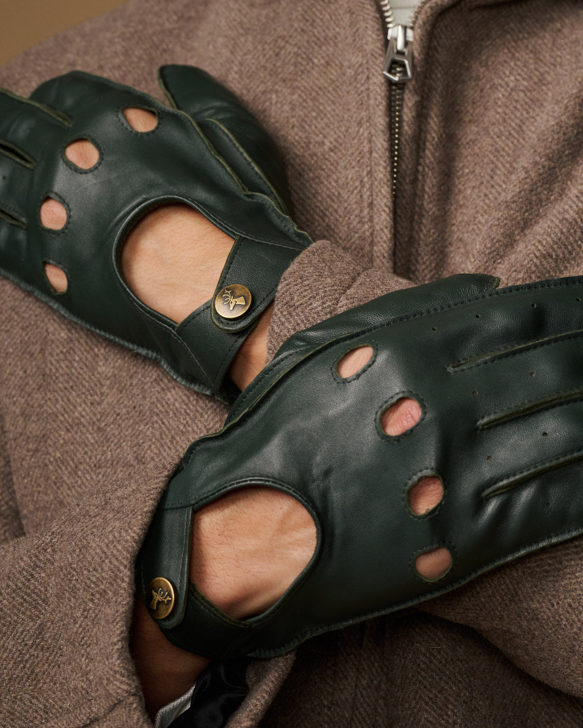 Dark green lambskin driving gloves close-up with perforated finger panels and button