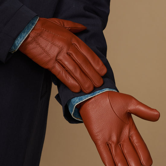 Cognac leather glove close-up with stitched fingers, wool cuff trim, touchscreen