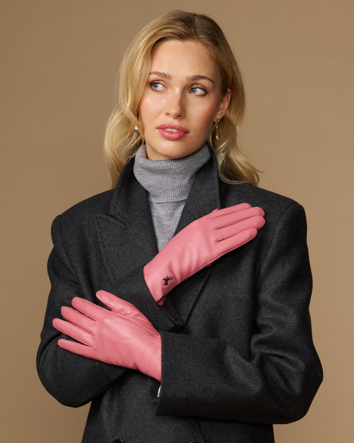 Women’s pink leather gloves crossed at chest, with small logo on the back