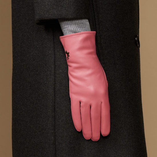Women’s pink leather glove on a coat sleeve, showing wrist seam and finger stitching