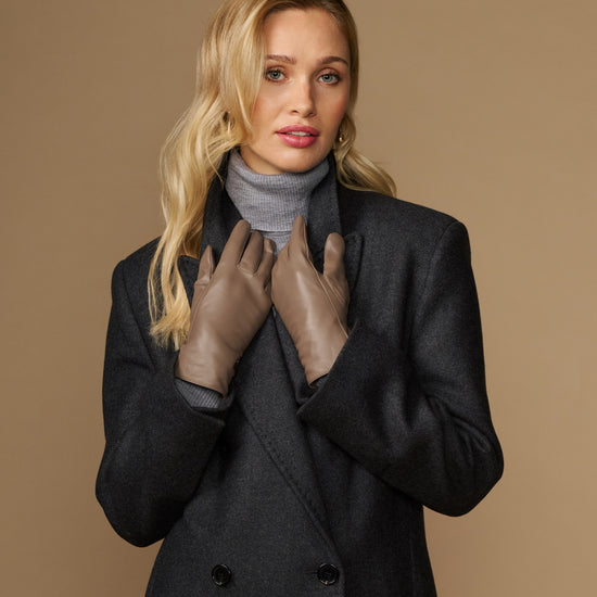 Women’s taupe leather gloves with snug fit, worn at chest level