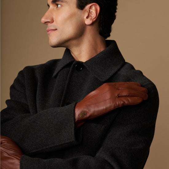 Cognac leather glove over hand with fleece-lined cuff, worn on forearm
