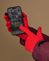 Red activity gloves with textured grip palms, used to operate a smartphone