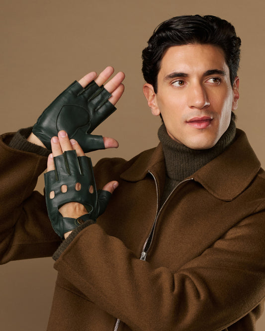 Dark green lambskin driving gloves with fingerless tips and perforated knuckles, worn on both hands