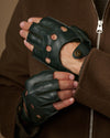 Close-up of dark green fingerless lambskin gloves with perforated fingers and adjustable wrist straps