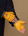 Yellow fingerless glove on open hand, stitched seams and knuckle perforations