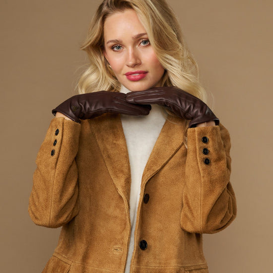 Brown fleece-lined leather gloves held up near coat hood, cuffs visible