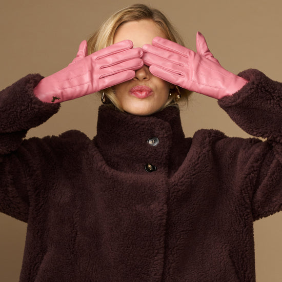 Pink leather gloves with dark sherpa lining, hands raised near face