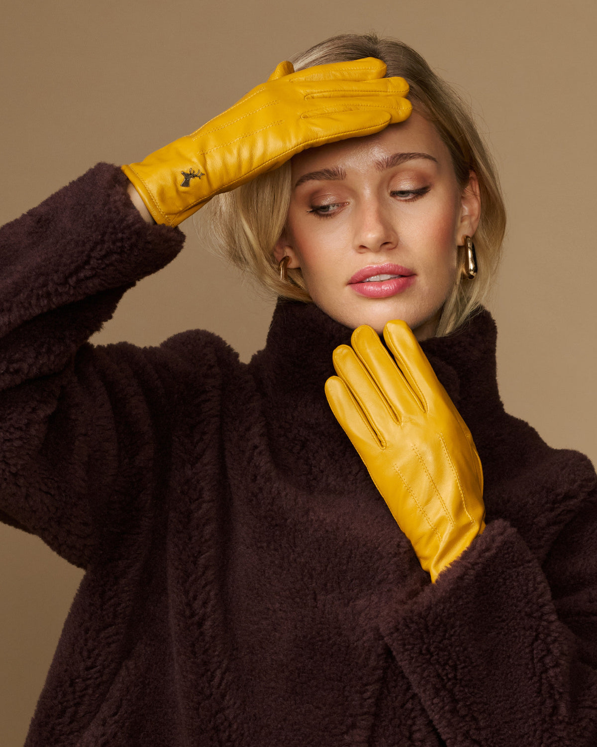 Yellow leather gloves with dark fleece cuff, held up near the face
