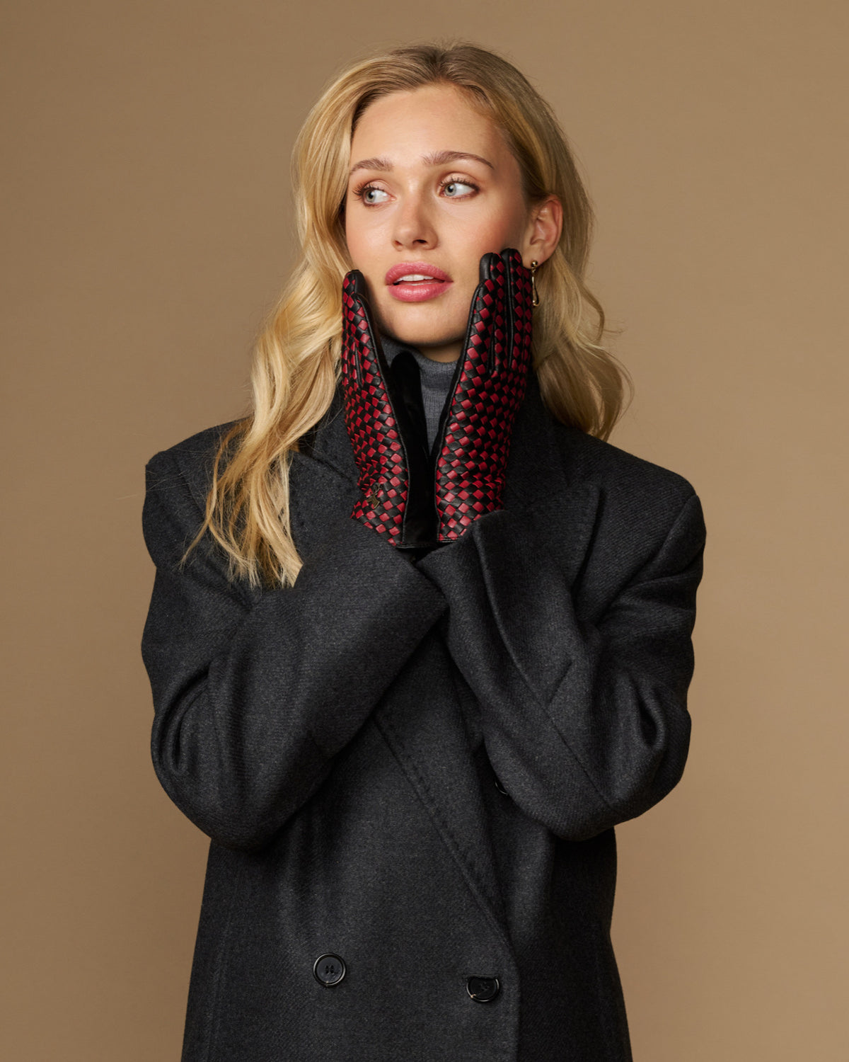 Women's black leather gloves with red-and-black checkered lining, worn at neckline
