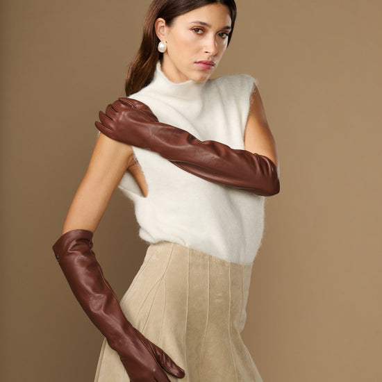 Women’s elbow-length brown lambskin leather gloves with silk lining, worn.