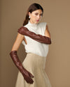 Women’s elbow-length brown lambskin leather gloves with silk lining, worn.