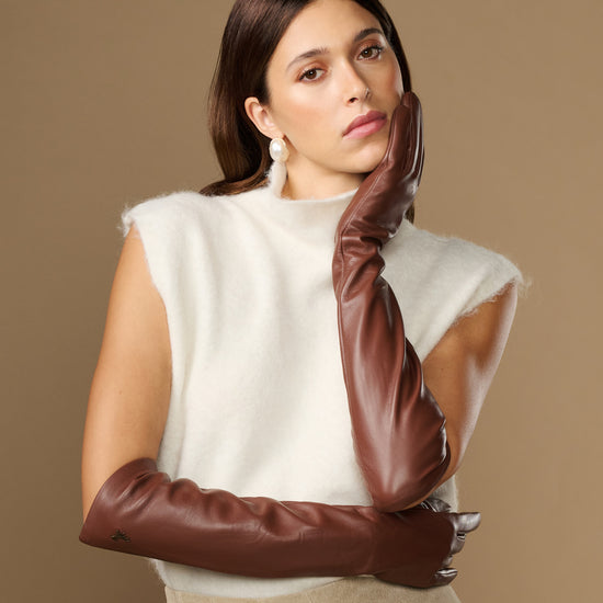 Women’s brown leather elbow gloves with smooth finish, worn across chest.