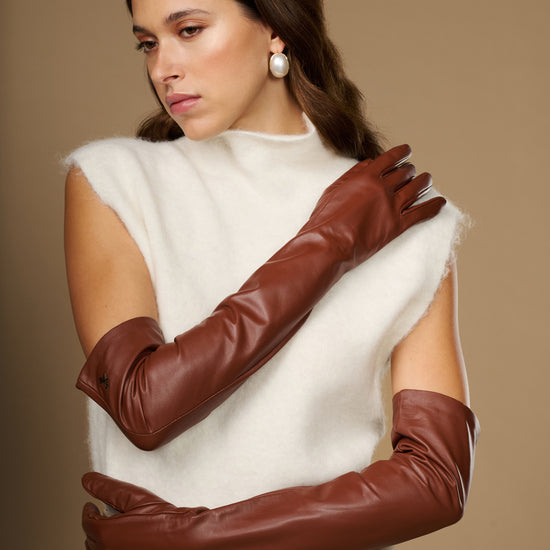 Chestnut brown leather opera gloves in a crossed-arm pose, long sleeves and cuffs