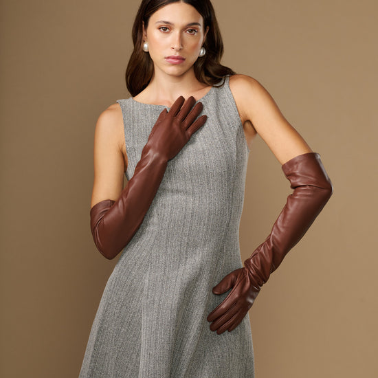 Women's chocolate-brown lambskin leather gloves, one hand raised with curved finger seams