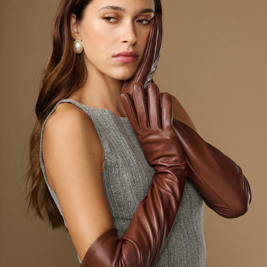 Women's chocolate-brown lambskin leather gloves, side view on raised hands with finger detailing