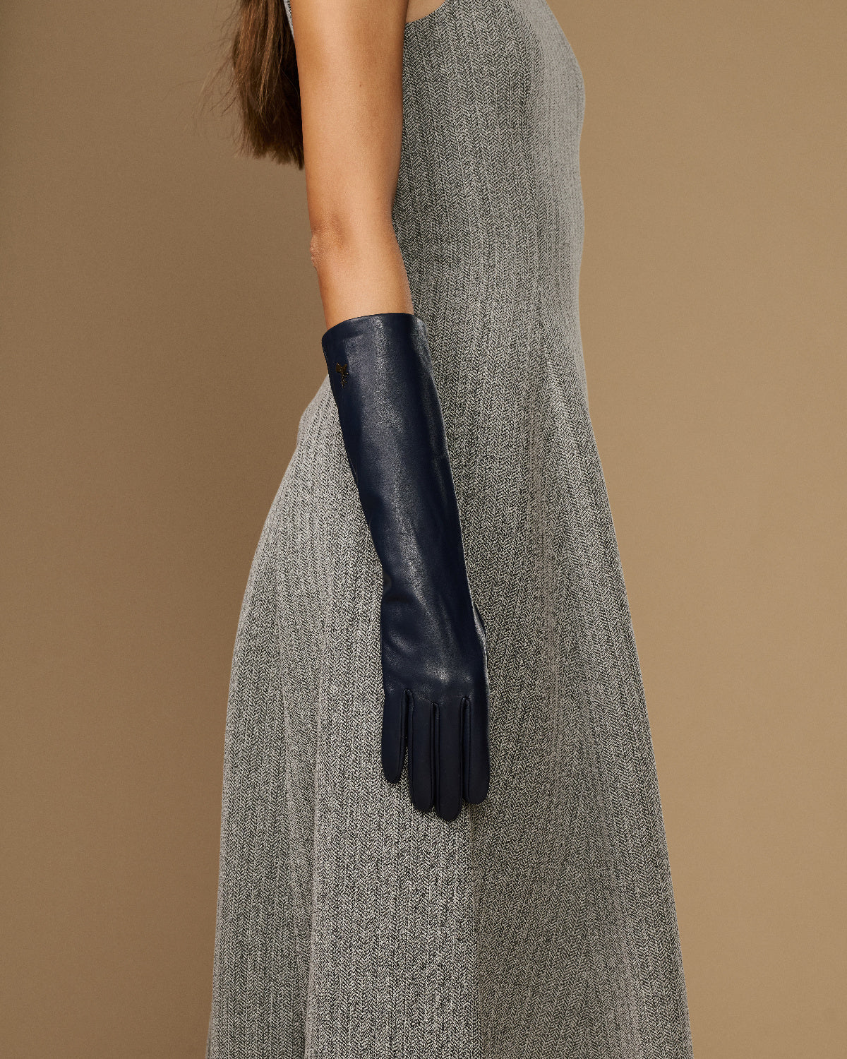 Women’s below-elbow dark blue leather glove on arm, smooth lambskin and snug cuff