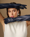 Navy leather opera gloves with long cuffs and silk lining, close-up with hands crossed
