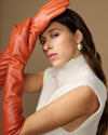 Close-up of orange leather elbow glove covering the raised hand and wrist