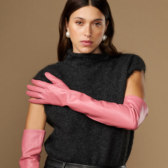 Women's pink leather gloves with long cuffs, arms crossed in front