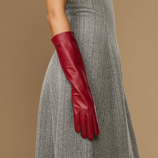 Red leather below-elbow glove on arm, showing long cuff and stitched fingertip seams