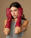 Women’s red leather below-elbow gloves covering hands and wrists, centered portrait view
