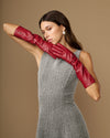 Single red leather glove extended across arm, highlighting below-elbow length and cuff