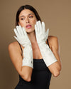 Women’s white lambskin leather below-elbow gloves held up, silk-lined
