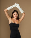 Women’s white lambskin leather below-elbow gloves on raised arms, silk-lined