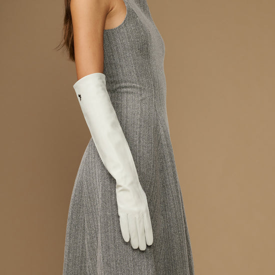 White elbow-length leather glove on arm, showing long cuff and finger seams