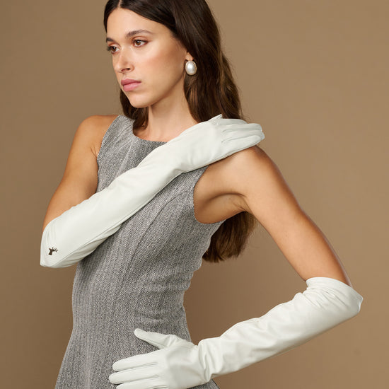 White elbow-length leather gloves with one hand flexed; fitted fingers and cuff