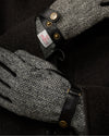 Men's gloves close-up: black leather cuff with gold snaps and gray herringbone panel.