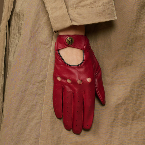 Red leather driving glove with open knuckle panel and round button emblem on cuff
