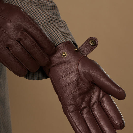 Brown leather glove close-up with press-stud at wrist and stitching detail
