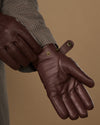 Brown leather glove close-up with press-stud at wrist and stitching detail