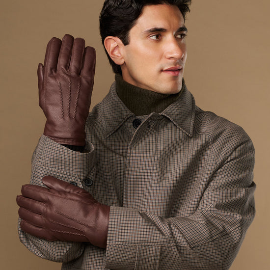 Brown leather gloves worn, one raised for a clear front view
