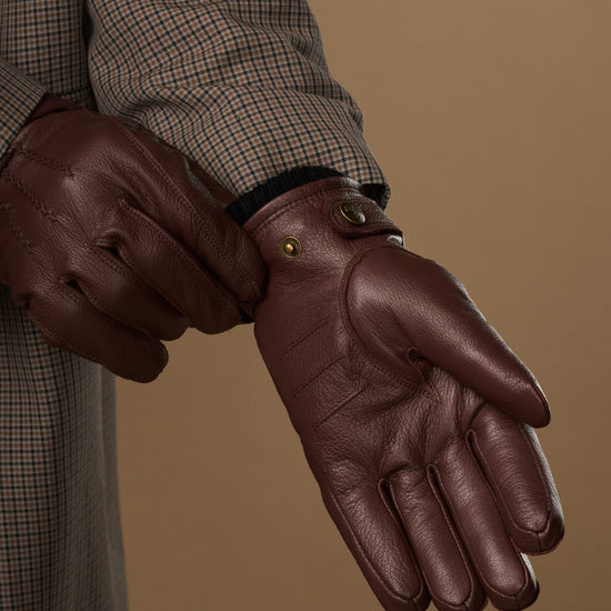 Brown leather glove close-up with press-stud wrist and finger stitching